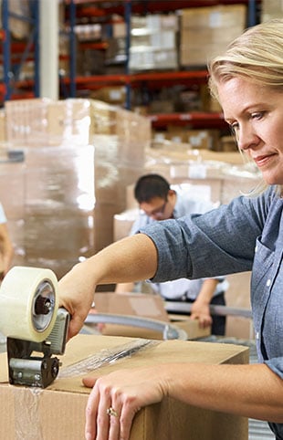 a person in the warehouse taping a shipping box