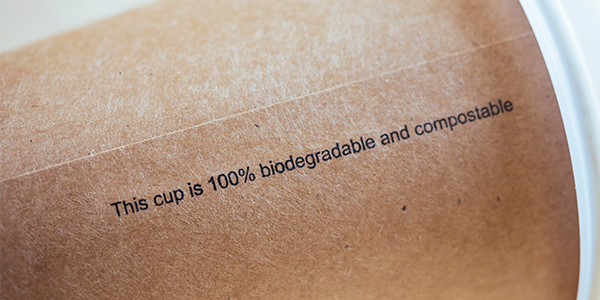 A paper cup says 100% biodegradable and compostable