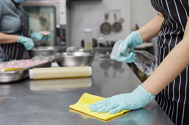 hospital kitchen staff disinfecting countertop surface