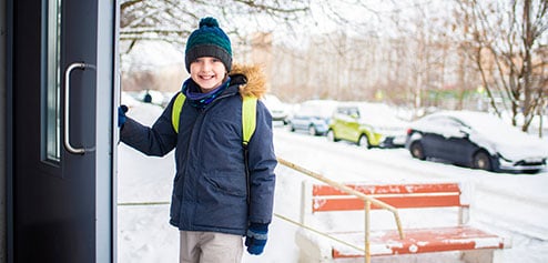 weather change - snowy day with a boy going into a school