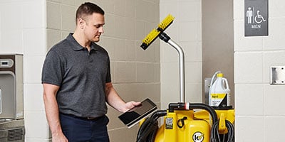 a school custodian operating Kaivac floor cleaning system with app