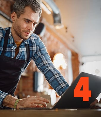 Coffee shop owner checking inventory on his laptop