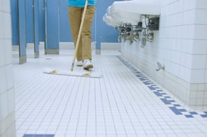 a school custodian wiping the restroom floor with 3M Easy Trap Dust sheet