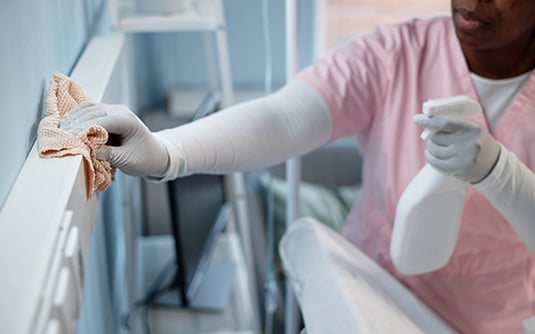 a healthcare worker disinfecting high touched surfaces