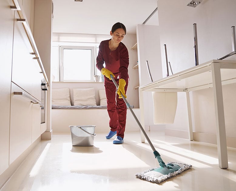 a female custodian wet mopping the floor