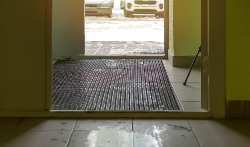 entryway_door_open_wet_floor_with_matting_snow_outside