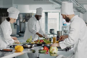 Three chefs making dishes in a commercial restaurant kitchen