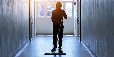 school custodian cleaning hallway floor