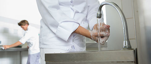 a kitchen staff washing hands with soap