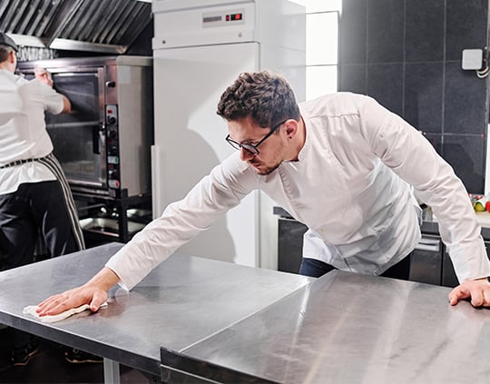 kitchen staff wiping down food prepping surface