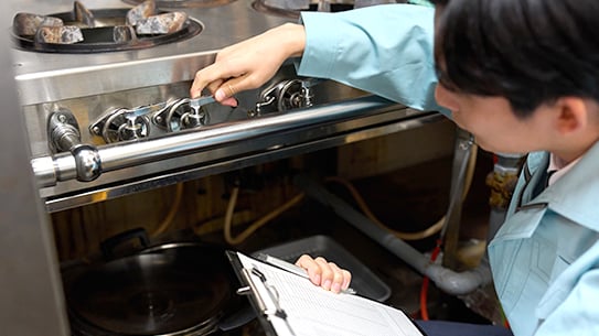 person inspecting for fire suppression system in the commercial kitchen