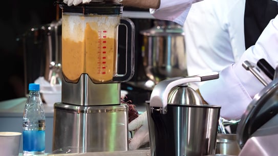 kitchen staff using a blender in commercial kitchen