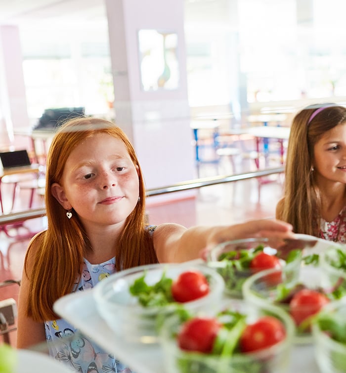 a couple of school students grabbing pre-packaged salads from school cafeteria