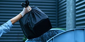 a person taking trash out to the dumpster